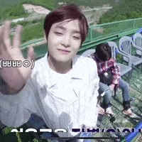 a man in a white shirt is waving at the camera while sitting on a staircase .