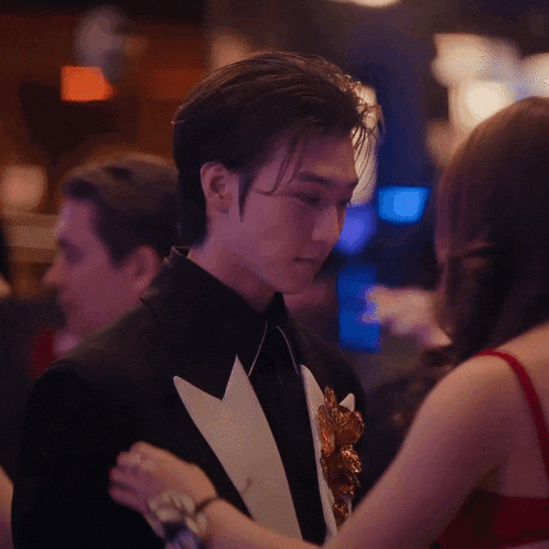 a man in a tuxedo is being held by a woman in a red dress