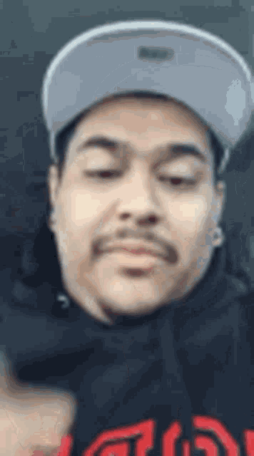 a man wearing a hat and a black shirt is making a face .