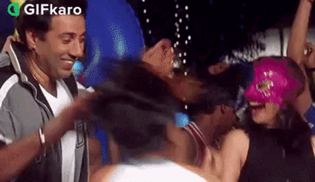 a group of people are dancing at a party with a man wearing a mask .