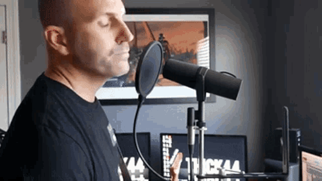 a man is singing into a microphone in front of a computer screen .