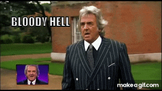 a man in a suit and tie is standing in front of a brick building with the words bloody hell above him