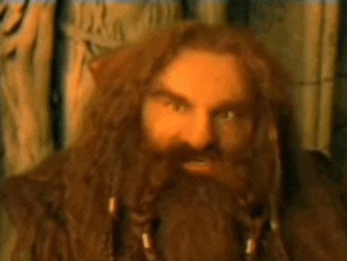 a man with a beard and long hair is sitting in a chair .
