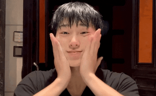 a young man wipes his face with his hands and looks at the camera