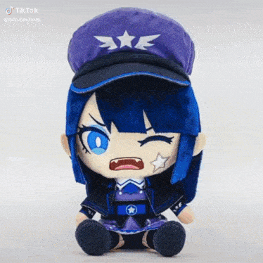 a stuffed doll with blue hair and a purple hat is sitting on a white table .