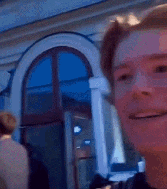 a close up of a man 's face with his mouth open and a window in the background .