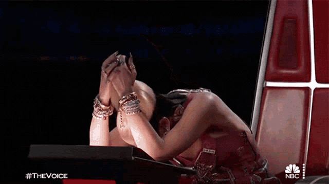 a woman is sitting in a chair with her hands on her face and the words #thevoice on the bottom
