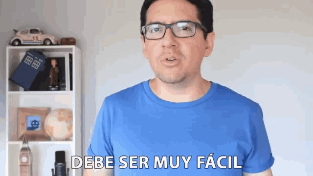 a man wearing glasses and a blue shirt says " debe ser muy facil "