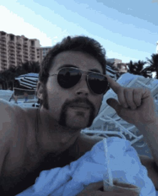 a shirtless man wearing sunglasses is laying on a towel