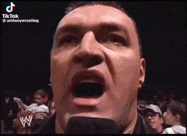 a close up of a man 's face with a microphone in his mouth .