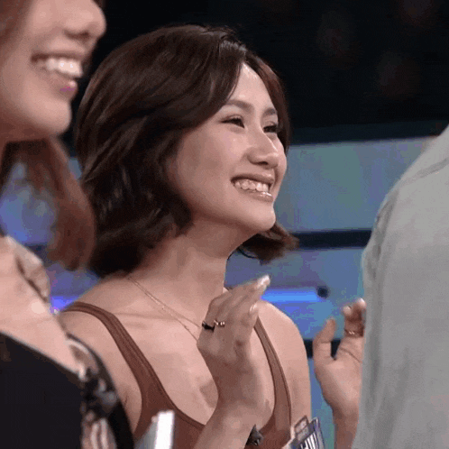 a woman in a brown tank top is smiling while holding a name tag that says ' a ' on it