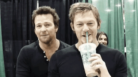 two men drinking from a starbucks cup with a straw .