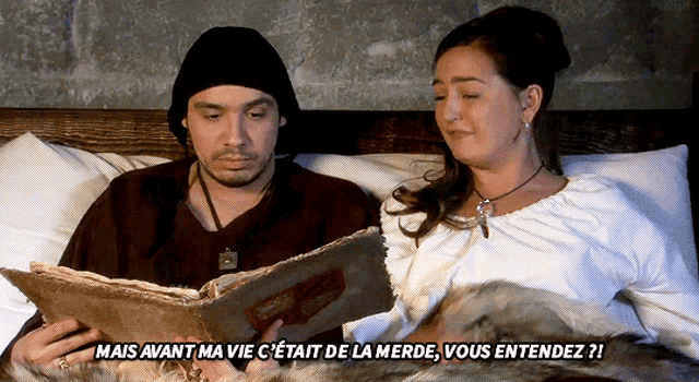 a man and a woman are laying in bed reading a book and the woman is saying mais avant ma vie c'etait de la merde