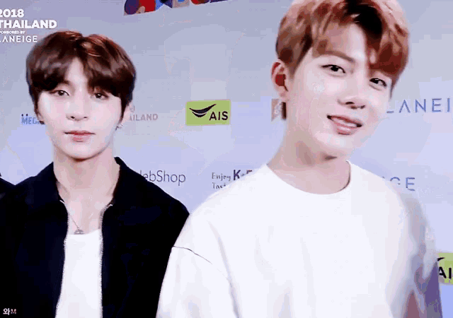 two young men are standing next to each other in front of a wall that says ais on it