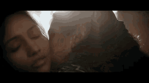 a man and woman are kissing in a dark room .