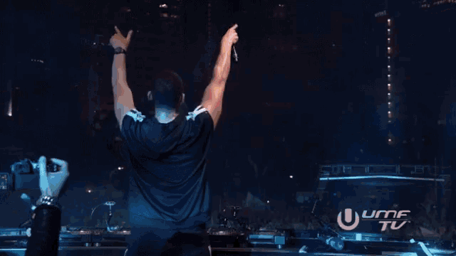 a man stands on a stage with his arms in the air in front of a sign that says ' umf tv '