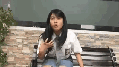 a young girl in a school uniform is sitting on a wooden bench .