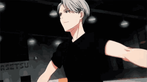a man in a black shirt is reaching out his arms towards another man in a dark room .