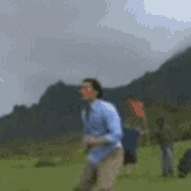 a blurry picture of a man standing in a grassy field .