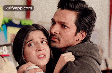 a man is holding a woman in his arms and making a face .