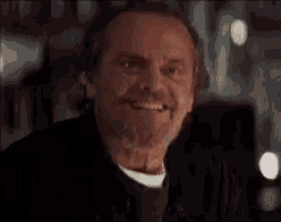 a close up of a man with a beard smiling in a dark room .