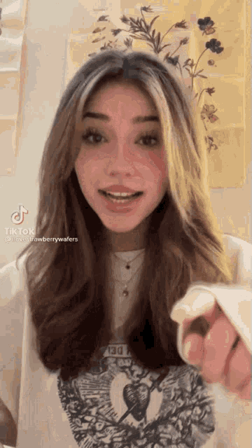 a girl with long brown hair is wearing a white t-shirt with a strawberry wafers logo on it .