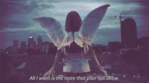a woman with angel wings is standing in front of a city skyline and says all i want is the taste that your lips allow .