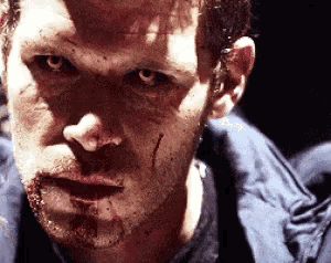 a man with blood on his face is looking at the camera