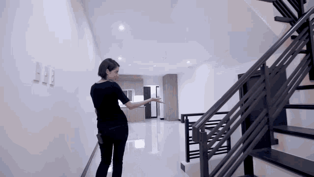 a woman in a black shirt is walking down a hallway