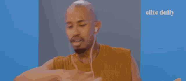 a man wearing ear buds is making a gesture in front of an elite daily ad