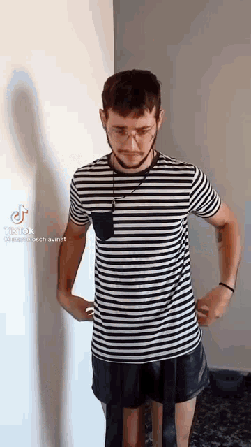 a man in a striped shirt and shorts is standing in a room .