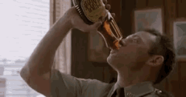 a man in a uniform is drinking from a bottle of beer .