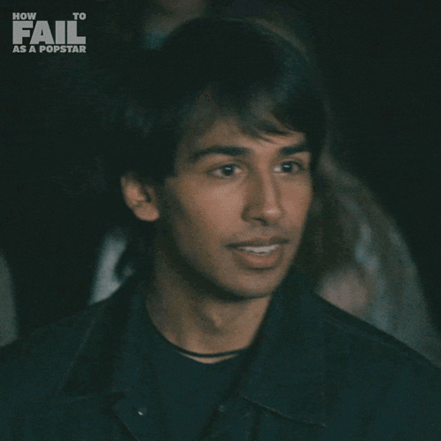 a young man says " yeah " in front of a poster for how to fail as a popstar