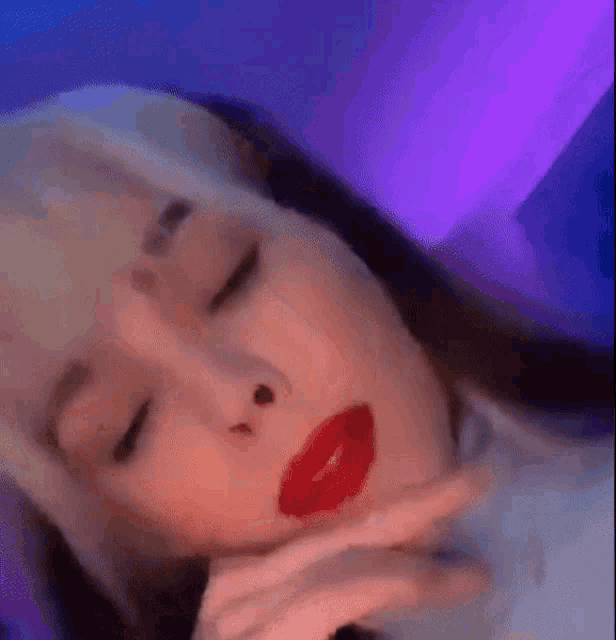 a close up of a woman 's face with red lipstick and a purple background .