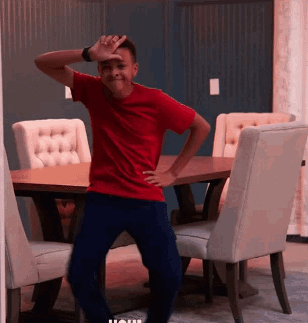 a boy in a red shirt is standing in front of a table and chairs