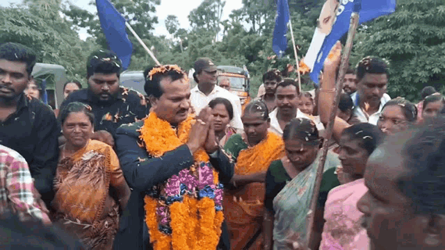 a man wearing a flower garland is surrounded by people