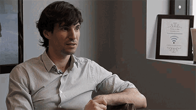 a man sitting in front of a wall with a picture on it