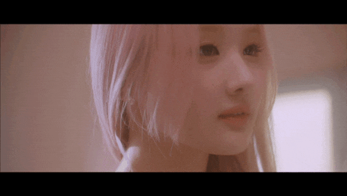 a close up of a woman 's face with pink hair