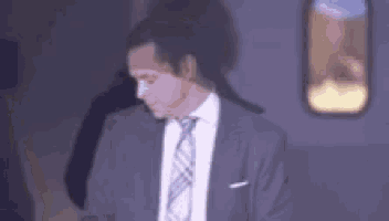 a man in a suit and tie is standing in front of a plane .