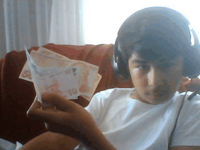 a boy wearing headphones is holding a 10 bill
