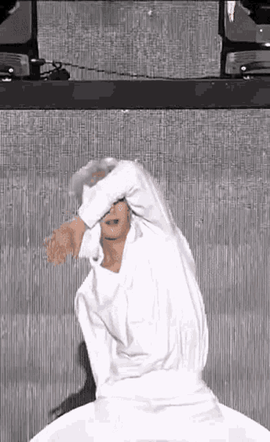 a man in a white shirt is dancing in front of a large screen .
