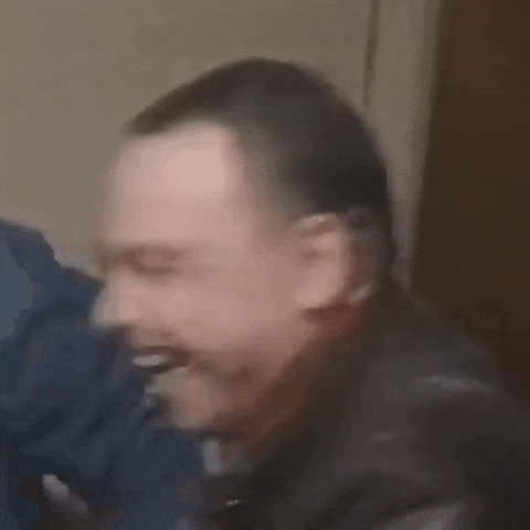 a man is smiling with his eyes closed and his mouth open in a close up .