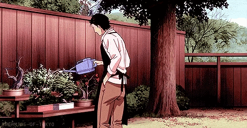 a man is watering plants with a blue watering can in a garden .