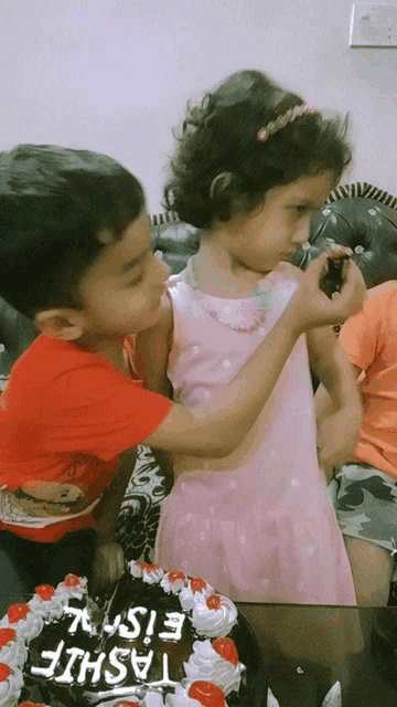 a boy and a girl are standing in front of a birthday cake that says tashil on it