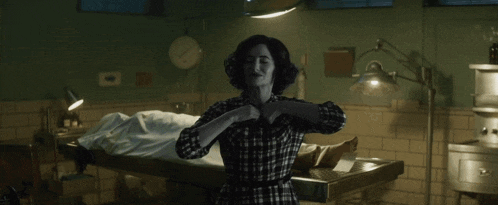 a woman in a plaid shirt is standing in a dark room