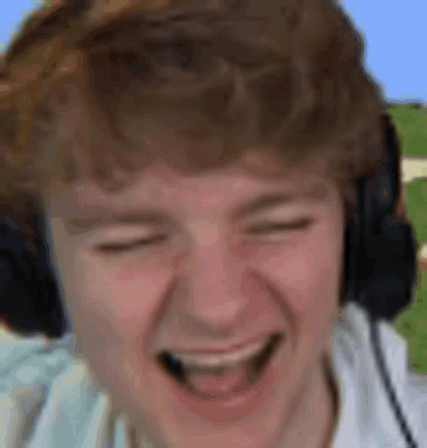 a young man wearing headphones is laughing with his eyes closed .