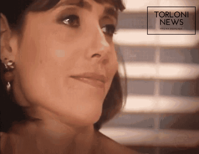 a close up of a woman 's face with a torloni news advertisement in the background