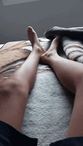 a person laying on a bed with their legs crossed and their feet up