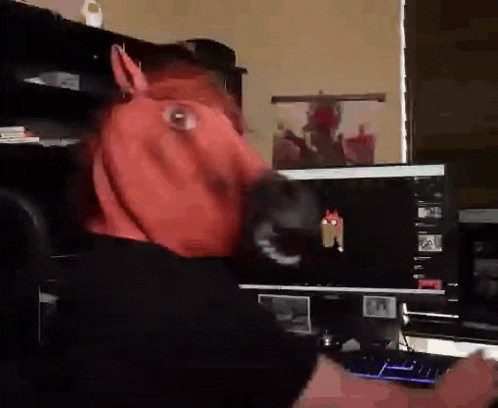 a person wearing a red horse head mask is playing a video game on a computer .