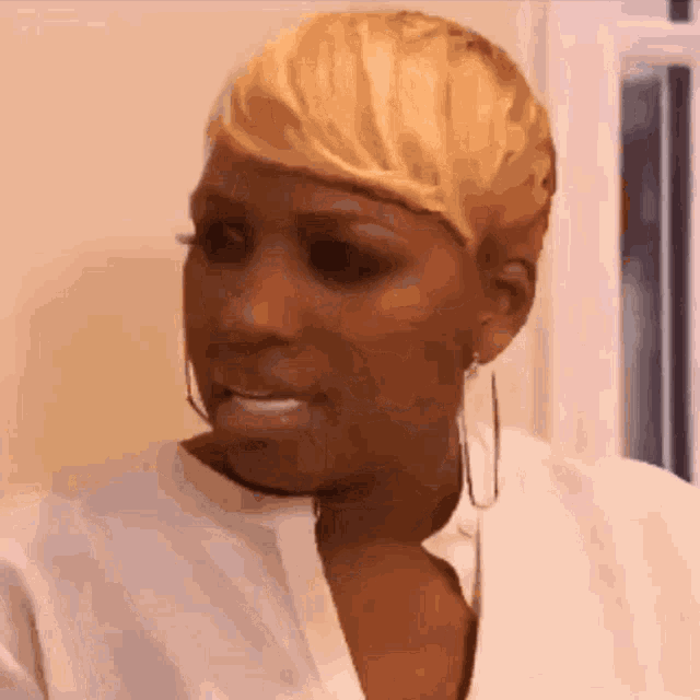 a woman with short blonde hair wearing hoop earrings